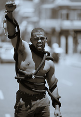 Image showing Protest, fist and man in rope and handcuffs in city protesting against discrimination, oppression or slavery and racism. Black lives matter, justice and angry male in street fighting for human rights