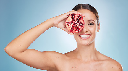 Image showing Face portrait, skincare and woman with pomegranate in studio on a blue background. Organic cosmetics, beauty and female model with product, fruit or food for vitamin c, nutrition and healthy diet.