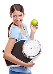 Image showing Apple, scale and diet of woman in studio isolated on white background for health, lose weight and portrait. Green fruit, body goals and model smile for her detox results, food commitment and wellness