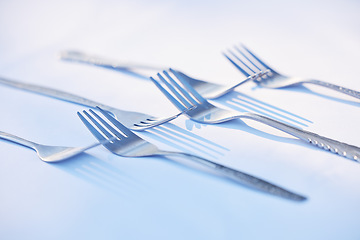 Image showing Fork, cutlery and symmetry with eating utensils on a table in an empty studio on a blue background from above. Kitchen, utensil and forks closeup ready for breakfast, lunch or dinner in a restaurant