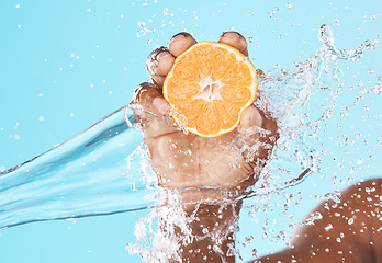 Image showing Water splash, orange in hand and studio background in healthy, vegan and nutrition food advertising, marketing or promotion mockup. Shower, hand holding fruit and vitamin c benefits in clean skincare
