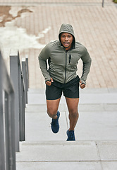 Image showing Fitness, runner or black man running on steps in exercise, training or cardio workout in Chicago. Mission, mindset or healthy athlete in hoodie with motivation or sports goals exercising on stairs