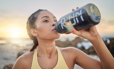 Image showing Health, fitness and woman drinking water at beach after running, exercise or workout. Sports, hydration and thirsty female athlete with water bottle on break after training for wellness at sunset.