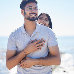 Image showing Hug, happy young couple at beach with travel and care on summer holiday by ocean, commitment and support outdoor. Partner, embrace and relationship with romantic date, man and woman on vacation