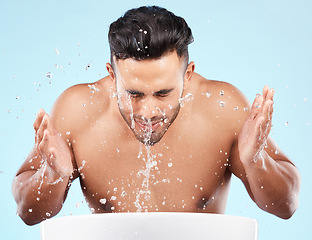 Image showing Face, water splash and skincare of man cleaning in studio isolated on a blue background. Hygiene, water drops and male model washing, bathing or grooming for healthy skin, facial wellness or beauty.