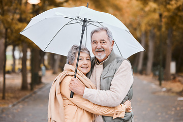 Image showing Winter, hug and senior couple in a park, retirement date and walking in Canada with an umbrella. Nature affection, smile and portrait of an elderly man and woman on a walk for happiness and love