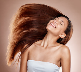 Image showing Hair care, beauty and woman in a studio with healthy, long and brown hair after a salon hair style. Cosmetics, happy and female model from Brazil with a keratin or botox treatment by brown background