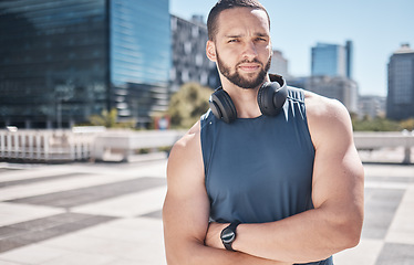 Image showing Portrait, fitness and city with a sports man standing arms crossed while listening to music furing his workout. Exercise, health and wellness with a male athlete training outdoor in an urban town