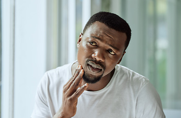 Image showing Sad, aesthetic and anxiety of black man with acne confused with face analysis in home bathroom mirror. Unhappy skincare man checking pimple problem in reflection with morning grooming routine.