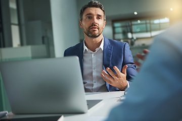 Image showing Laptop, meeting and interview with a business man talking to a candidate for the hiring or recruitment process. Computer, feedback or review with a male employee sitting in a human resources office