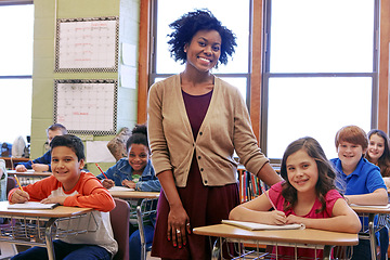 Image showing Education, learning and teacher in classroom with kids writing exam or test at Montessori school. Portrait of black woman, happy children at desk and monitoring growth and development for school kids