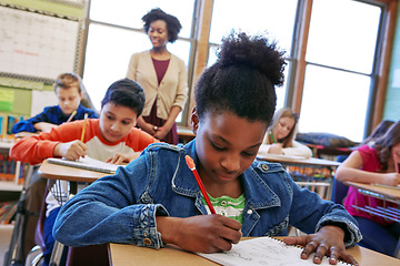 Image showing Children, education and school with a student black girl writing in a book while sitting in class for learning. Study, notebook and scholarship with a female child at her desk in the classroom