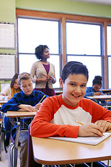 Image showing Portrait, education or kid in classroom with smile writing in notebook for learning, research or study for exam. Scholarship, thinking or students happy in school for test, academy or assessment