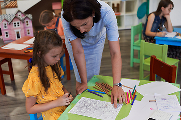 Image showing Creative kids during an art class in a daycare center or elementary school classroom drawing with female teacher.