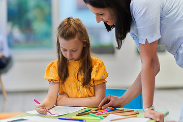 Image showing Creative kids during an art class in a daycare center or elementary school classroom drawing with female teacher.