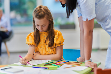 Image showing Creative kids during an art class in a daycare center or elementary school classroom drawing with female teacher.