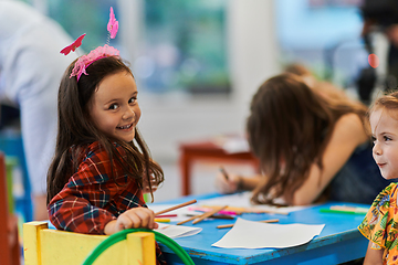 Image showing Creative kids during an art class in a daycare center or elementary school classroom drawing with female teacher.