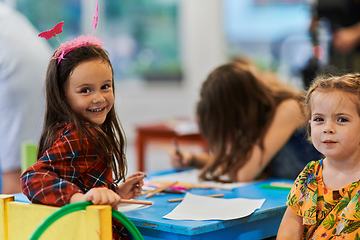 Image showing Creative kids during an art class in a daycare center or elementary school classroom drawing with female teacher.