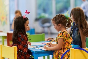 Image showing Creative kids during an art class in a daycare center or elementary school classroom drawing with female teacher.