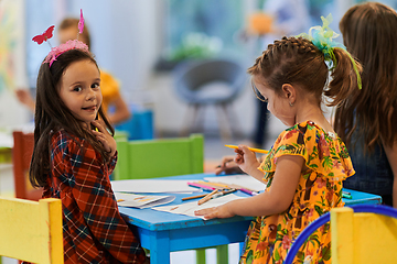 Image showing Creative kids during an art class in a daycare center or elementary school classroom drawing with female teacher.