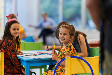 Image showing Creative kids during an art class in a daycare center or elementary school classroom drawing with female teacher.