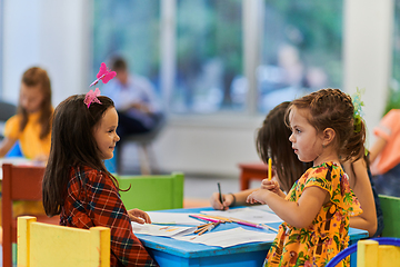 Image showing Creative kids during an art class in a daycare center or elementary school classroom drawing with female teacher.