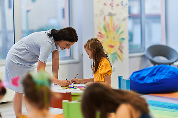 Image showing Creative kids during an art class in a daycare center or elementary school classroom drawing with female teacher.