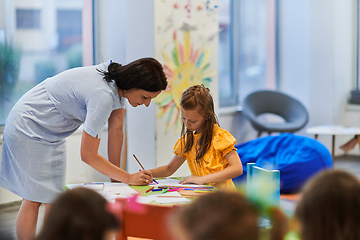 Image showing Creative kids during an art class in a daycare center or elementary school classroom drawing with female teacher.