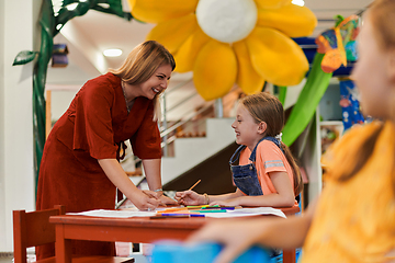 Image showing Creative kids during an art class in a daycare center or elementary school classroom drawing with female teacher.