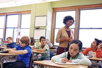 Image showing Children, education or kids in classroom writing in notebook for learning, research or study for exam with teacher. Scholarship, thinking or students in school for test, academy or assessment