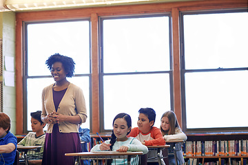 Image showing Learning, education and students with teacher in classroom or primary school. Scholarship, development and children with books writing test, exam and studying with happy black woman and educator.