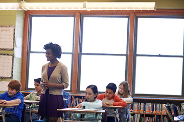 Image showing School, teacher and children in student classroom for education, knowledge and development. Black woman in class to teach diversity kids or students together for learning, studying and writing test