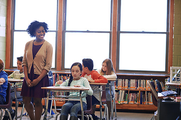 Image showing Education, learning and students with teacher in classroom or primary school. Scholarship, development and children with books writing and studying with happy black woman and educator checking work.