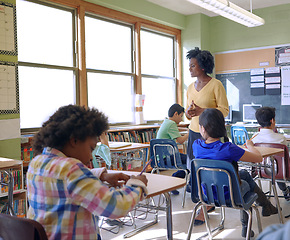 Image showing School, children and teacher in a classroom while talking to kids to study and learn knowledge and education. Diversity group students in class writing and learning for future, development and growth