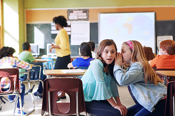 Image showing School, friends and whispering in classroom for secret, gossip or chatting during teaching lesson. Sneaky female learners sharing quiet information secretly in ear at class while teacher is busy