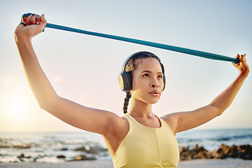 Image showing Headphones, beach and woman with band stretching while streaming music, radio or podcast. Sunset, sports and female training with resistance band for health, fitness and wellness outdoors by ocean.