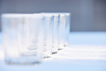 Image showing Glass, crockery and mockup with a row of drinking glasses on a table in a studio or restaurant for fine dining. Space, glassware and drinks with a group of cups in a line for a beverage while dining