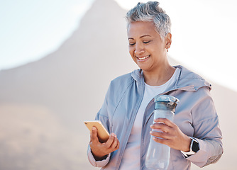 Image showing Running, water and phone with senior woman in mountain for jogging, workout and cardio training. Social media, progress tracker and fitness app with runner on path checking mobile for endurance goals