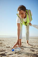 Image showing Volunteer, charity and beach cleanup with a black woman picking up plastic bottle garbage from the sand. Recycle, cleaning or earth day with a female going green for the environment or sustainability