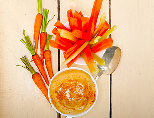 Image showing fresh hummus dip with raw carrot and celery