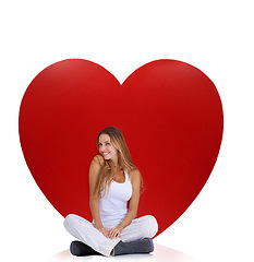 Image showing Portrait, studio and woman sitting by heart isolated on a white background. Beauty, love and smile of happy female model near big symbol for romance, affection or romantic emoji, care or empathy.