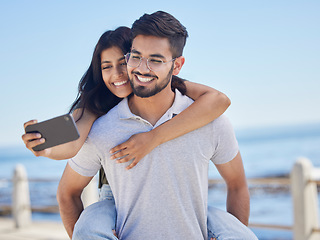 Image showing Phone selfie, ocean and couple hug, bond and enjoy time together for peace, freedom or romantic date. Sea beach, memory photo and man piggyback woman on fun travel holiday in Rio de Janeiro Brazil