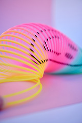 Image showing Rainbow, slinky toy and color spiral in studio for neon background for flexible, abstract or creative vaporwave aesthetic wallpaper. Colorful plastic spring backdrop for art, relax and happiness