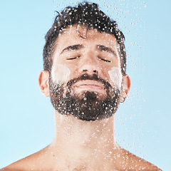 Image showing Water, man with face and cream for cleaning in shower with hygiene, grooming and skincare against blue studio background. Clean, model with water drops and facial, natural treatment and cosmetic care