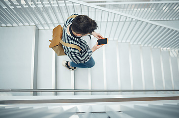 Image showing Phone, stairs and education with a student man walking down a staircase at university or college. Mobile, study and top view with a male pupil taking steps to get to class for learning or development