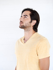 Image showing Casual, thinking and man looking up in a studio while being thoughtful or wondering for an idea. Pensive, daydreaming and young male model from Canada with stylish tshirt isolated by white background