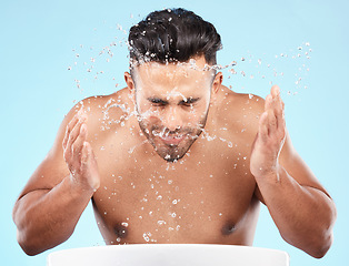 Image showing Face, water splash and skincare of man cleaning in studio isolated on a blue background. Hygiene, water drops and male model washing, bathing or grooming for healthy skin, facial wellness or beauty.