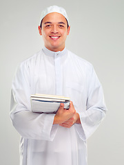 Image showing Islamic man, smile portrait and books for learning standing in white background for Arabic culture. Young person, smile and religion faith, hope or studying for Muslim education isolated in studio