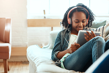 Image showing Digital tablet, headphones and black woman on the sofa to relax while listening to music, radio or podcast. Rest, technology and African lady watch a video on mobile device in her living room at home