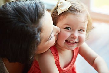 Image showing Portrait of a baby with her mother kissing her cheek while playing, bonding and spending time together. Happy, smile and girl infant child sitting with her mom in their modern family home with love.